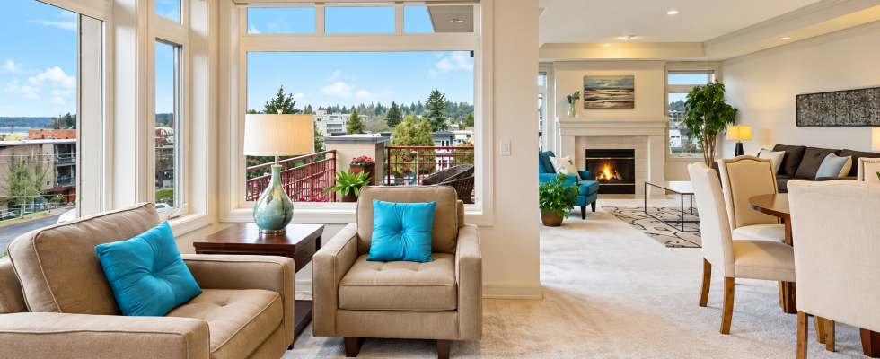 Illustrative bright open-plan living room with large windows, lounge seating, and dining area